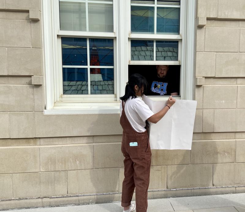 Madison Drake explains her work through an open window to teacher Travis Wharton.